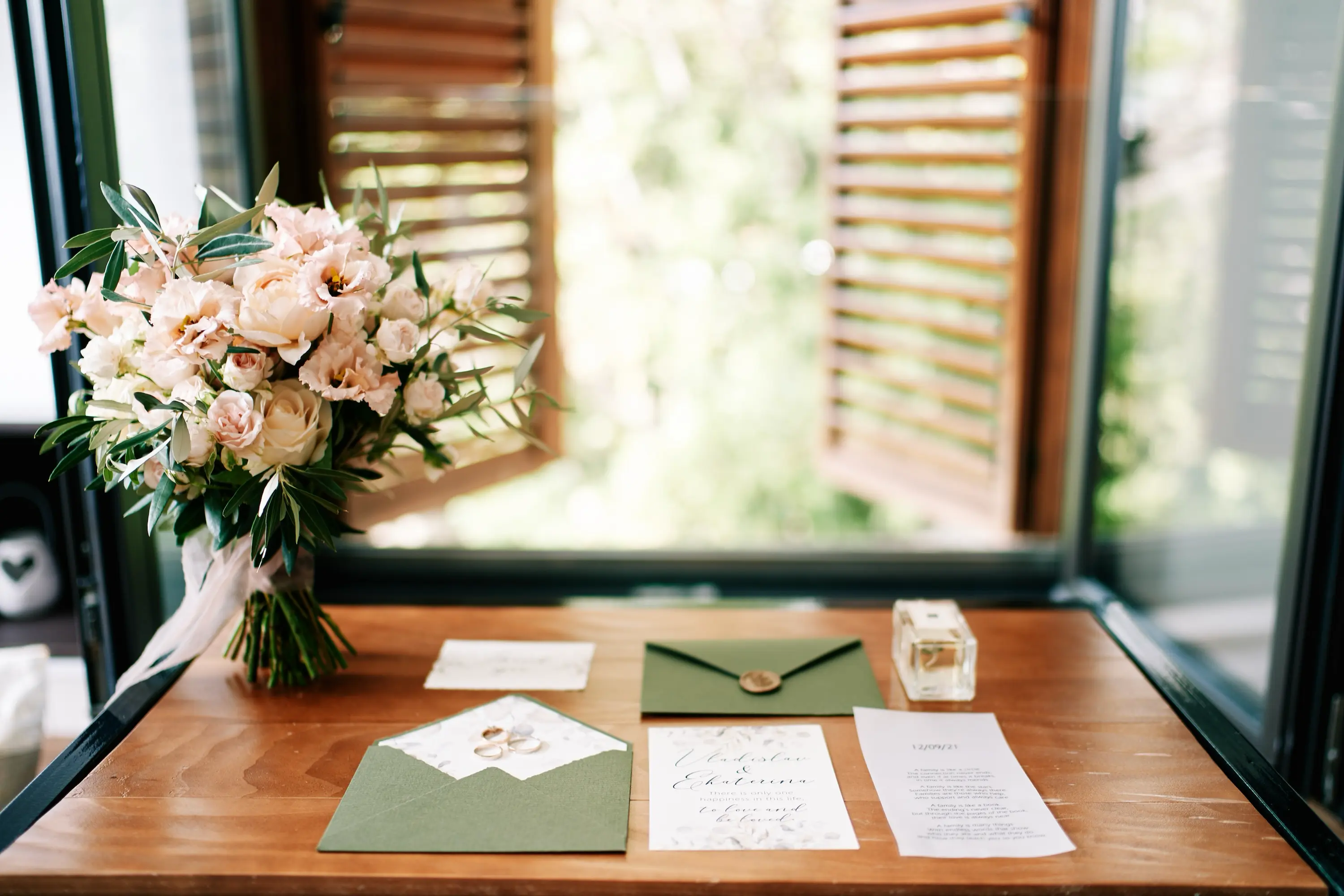 Wedding invitations on a desk next to flowers.